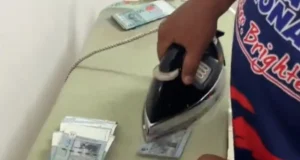 Lelaki menggosok nota RM50 di rumah untuk Raya kerana kekurangan masa.