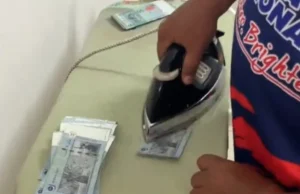 Lelaki menggosok nota RM50 di rumah untuk Raya kerana kekurangan masa.