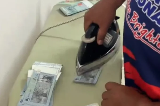 Lelaki menggosok nota RM50 di rumah untuk Raya kerana kekurangan masa.